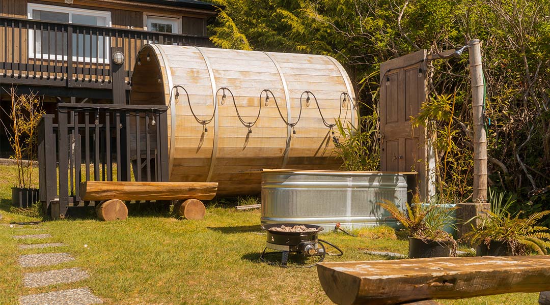 Wood-fired outdoor sauna at Little Beach Resort nestled among trees.