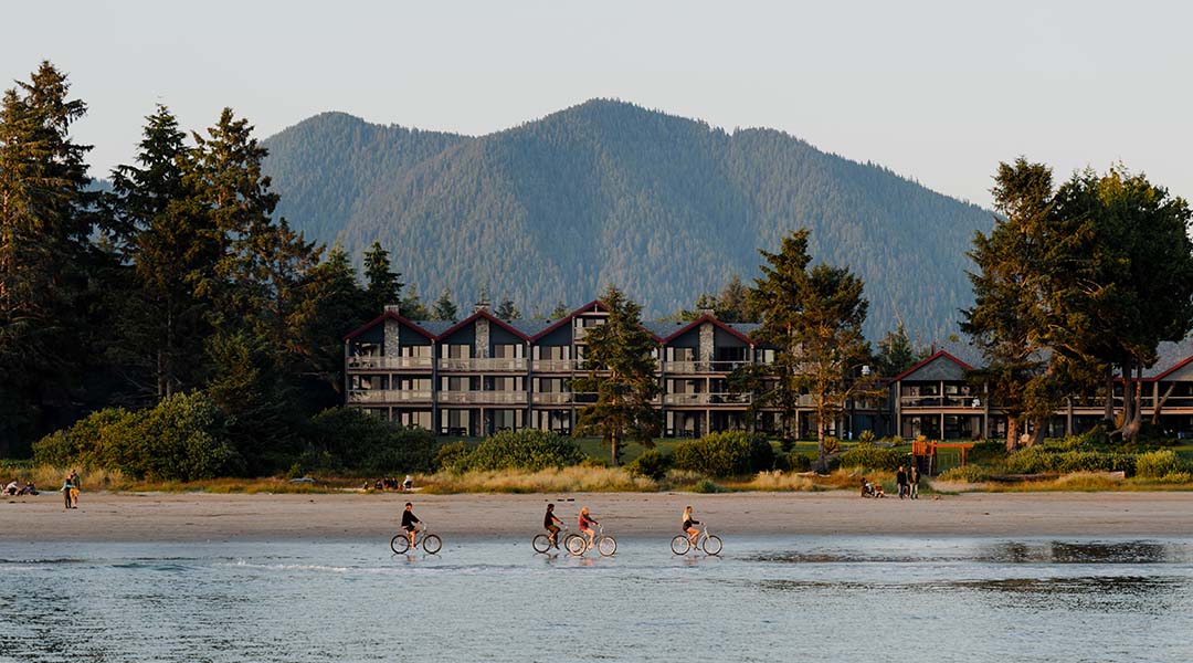 Exterior of hotel with people riding bikes on the beach