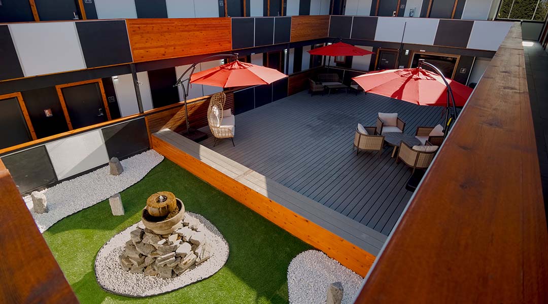 Courtyard at Coast Metro Vancouver featuring a water fountain, seating areas, and red umbrellas.
