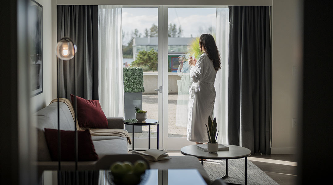 Bright hotel suite interior with floor-to-ceiling windows and waterfront view