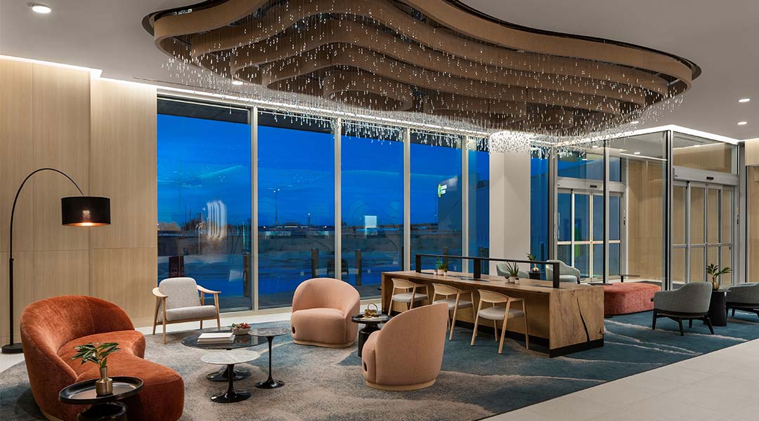 Modern hotel lobby with stylish seating, large windows, and a ceiling light fixture.