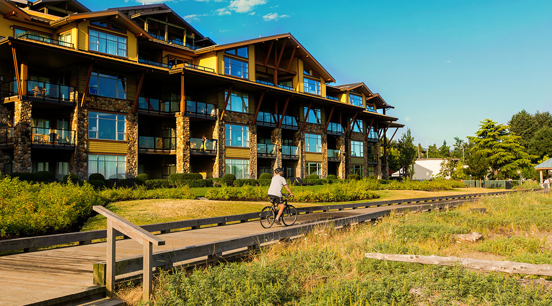 Person on bike cycling on a wooden boardwalk at The Beach Club Resort in Parksville