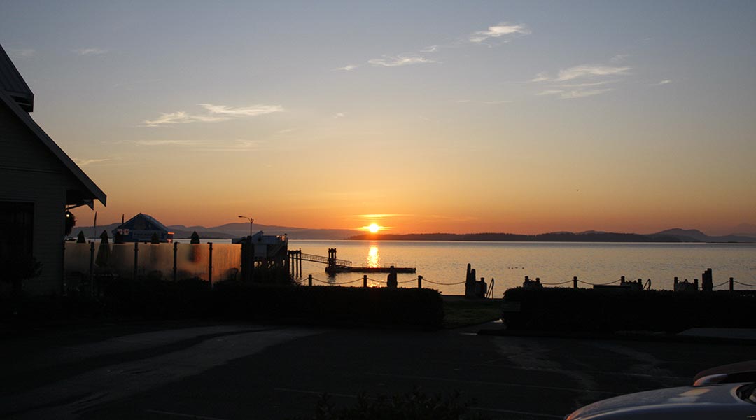 View of ocean and silhouette of buildings outside the Sidney Waterfront Inn and Suites on Vancouver Island at sunrise