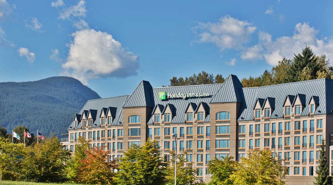 The exterior building of the Holiday Inn and Suites North Vancouver near the mountains