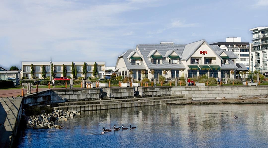 The exterior building of the Sidney Waterfront Inn and Suites by the ocean water on Vancouver Island