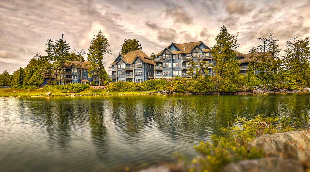 Exterior of Waters Edge Shoreside Suites with ocean in front and clouds in the sky in Ucluelet