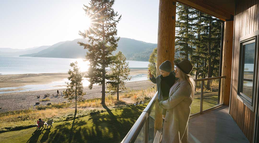 Family standing on balcony overlooking the beach and lake at Quaaout Lodge and Spa in Chase BC