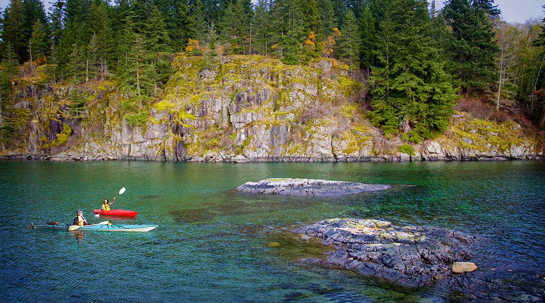 Two kayakers kayaking in the ocean nearby the Gowlland Harbour Resort on Quadra Island