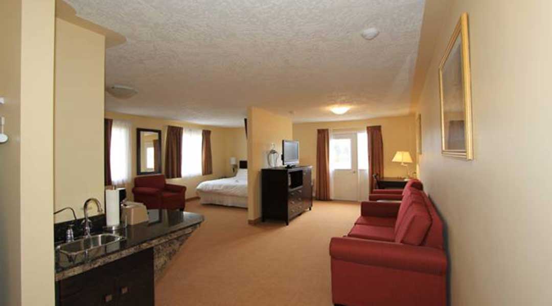 Living area and kitchenette with bed in the background in the VIP suite at Sunshine Inn in Smithers BC