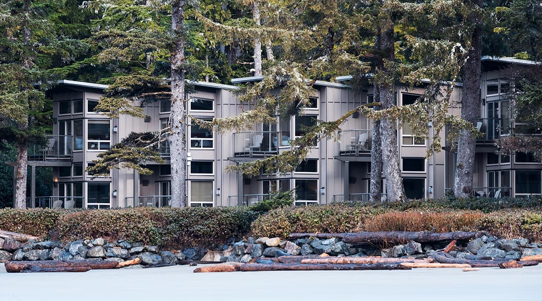The exterior building of the Pacific Sands Beach Resort and the patios near Cox Bay Beach in Tofino