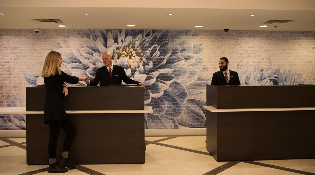 Employees helping guest at the front desk in lobby at the Victoria Marriott Inner Harbour in downtown Victoria