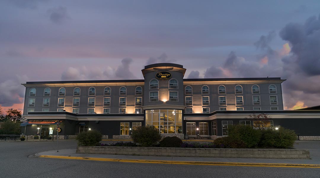 Front view of the exterior building of the Prestige Treasure Cove Hotel in Prince George during sunset
