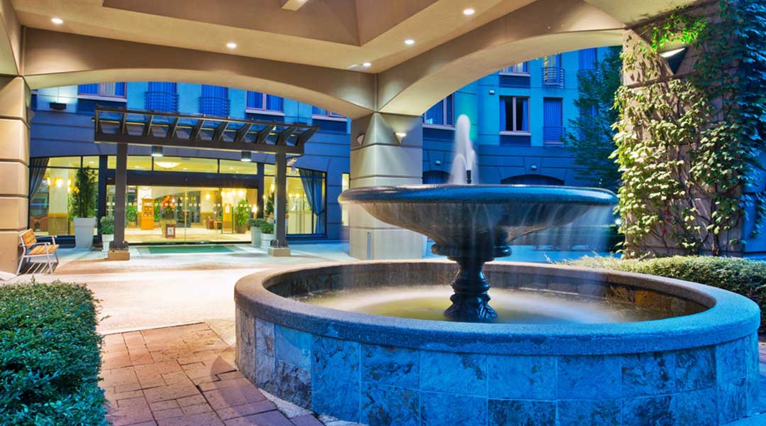 The exterior entrance and fountain of the Holiday Inn and Suites North Vancouver at night