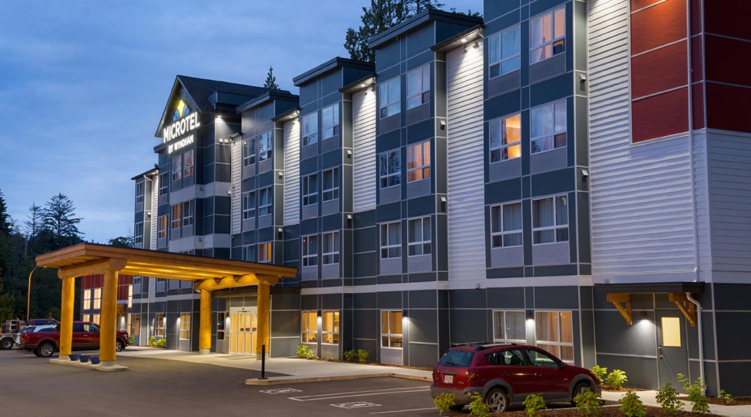 The exterior building and parking lot of the Microtel Inn and Suites by Wyndham Ladysmith Oyster Bay at dusk