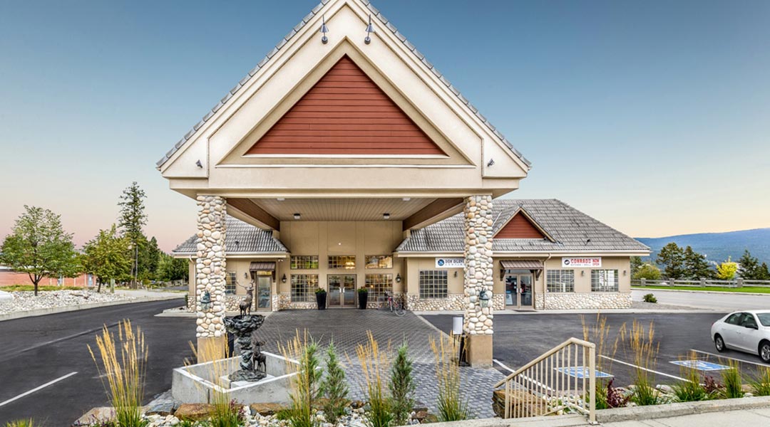 The exterior building and parking lot of the Prestige Radium Hot Springs Resort during the daytime
