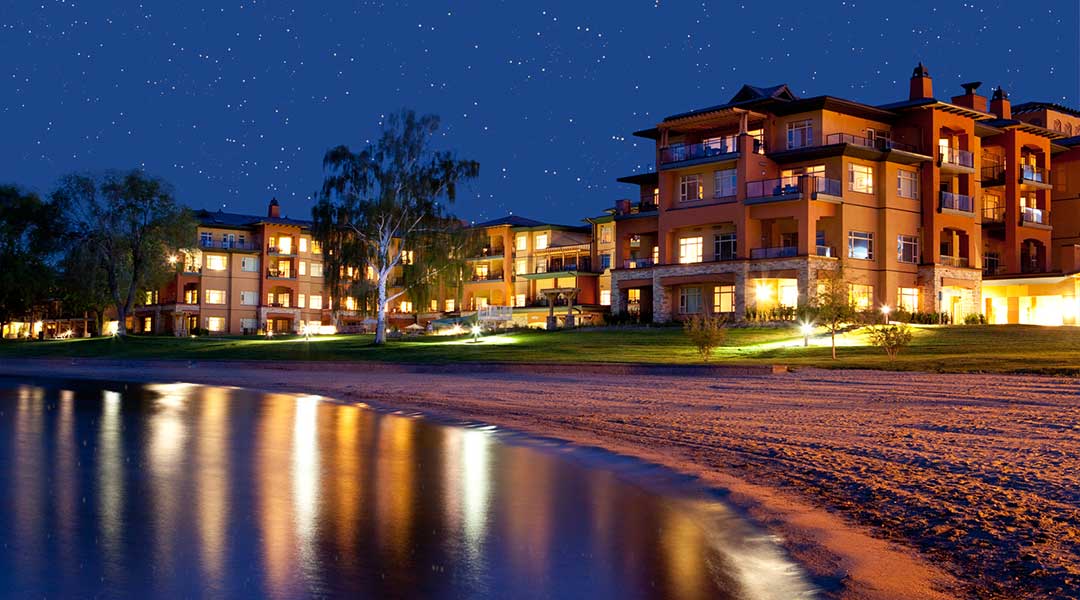 Beach in the evening with reflection of lights from resort on the lake at Watermark Beach Resort in Osoyoos Okanagan