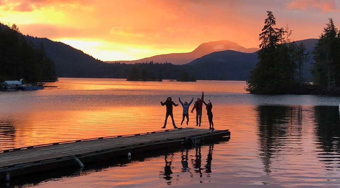 People standing on dock at sunset with purple skies at Ruby Lake Resort in Madeira Park on the Sunshine Coast