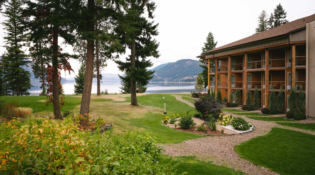 Pathway leading towards Quaaout Lodge and Spa with trees and grass surrounding in Chase BC