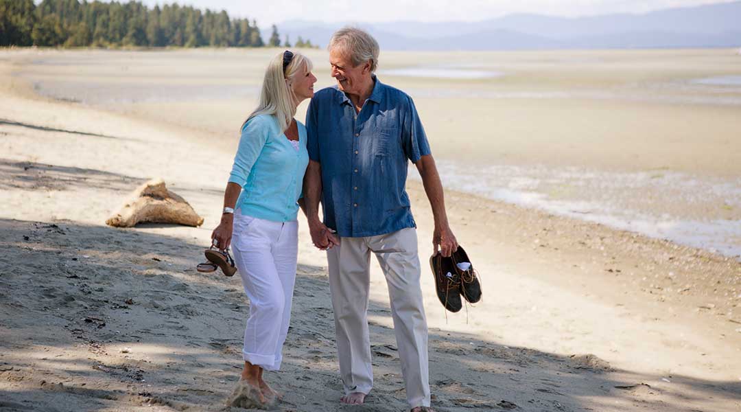 Couple walking along beach with shoes in hand at Tigh Na Mara Resort and Spa in Parksville
