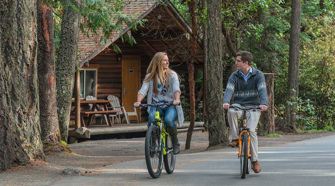 Couple biking side by side along path from cottage at Tigh Na Mara Resort and Spa in Parksville