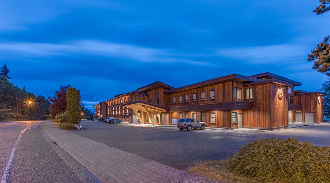Exterior of Kwa Lilas Hotel at dusk with parking lot out front in Port Hardy