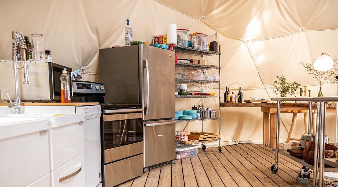 The kitchen area with stove and fridge inside the social dome at the Haida Gwaii Glamping Co