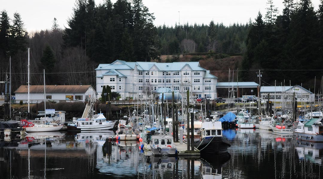 The marina with boats and the exterior of the Quarterdeck Resort and Marina in Port Hardy