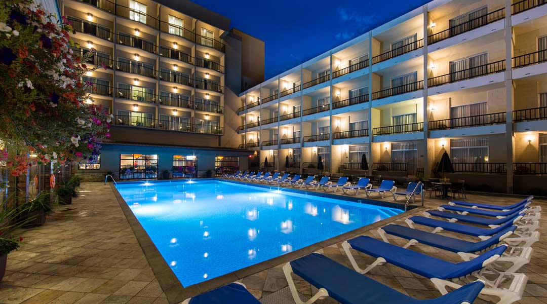 Overview of the outdoor pool and lounging chairs at the Coast Capri Hotel in Kelowna in the Thompson Okanagan in the evening