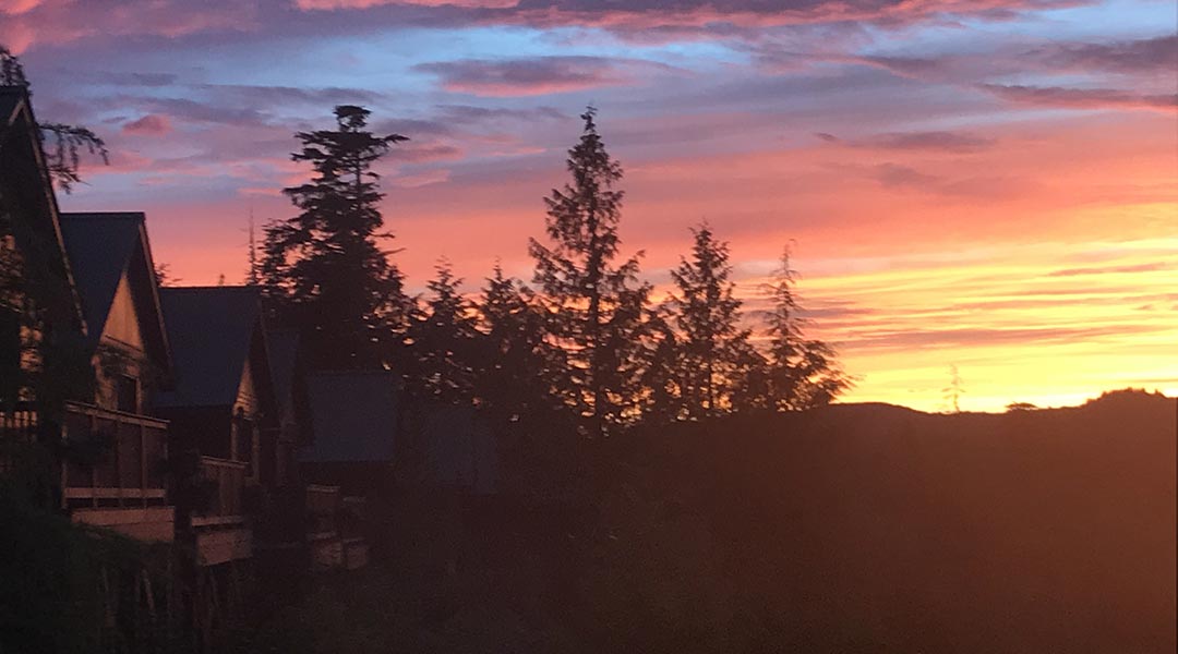 View of cotton candy skies during sunset next to the exterior of the wooden cottages at Bear Cove Cottages in Port hardy