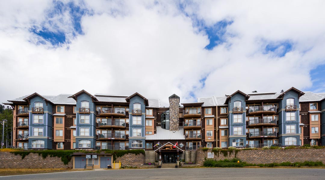 Exterior of Mount Washington Alpine Resort with blue skies and fluffy clouds on Vancouver Island